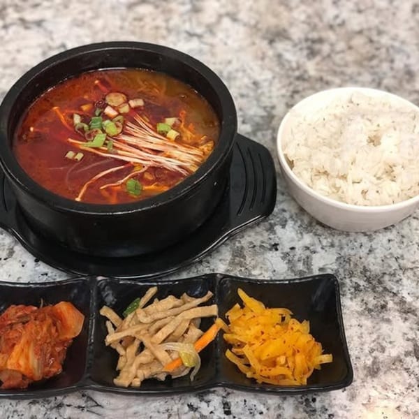 A Korean spicy soup with enoki mushrooms and green onions, served with rice and three side dishes.
